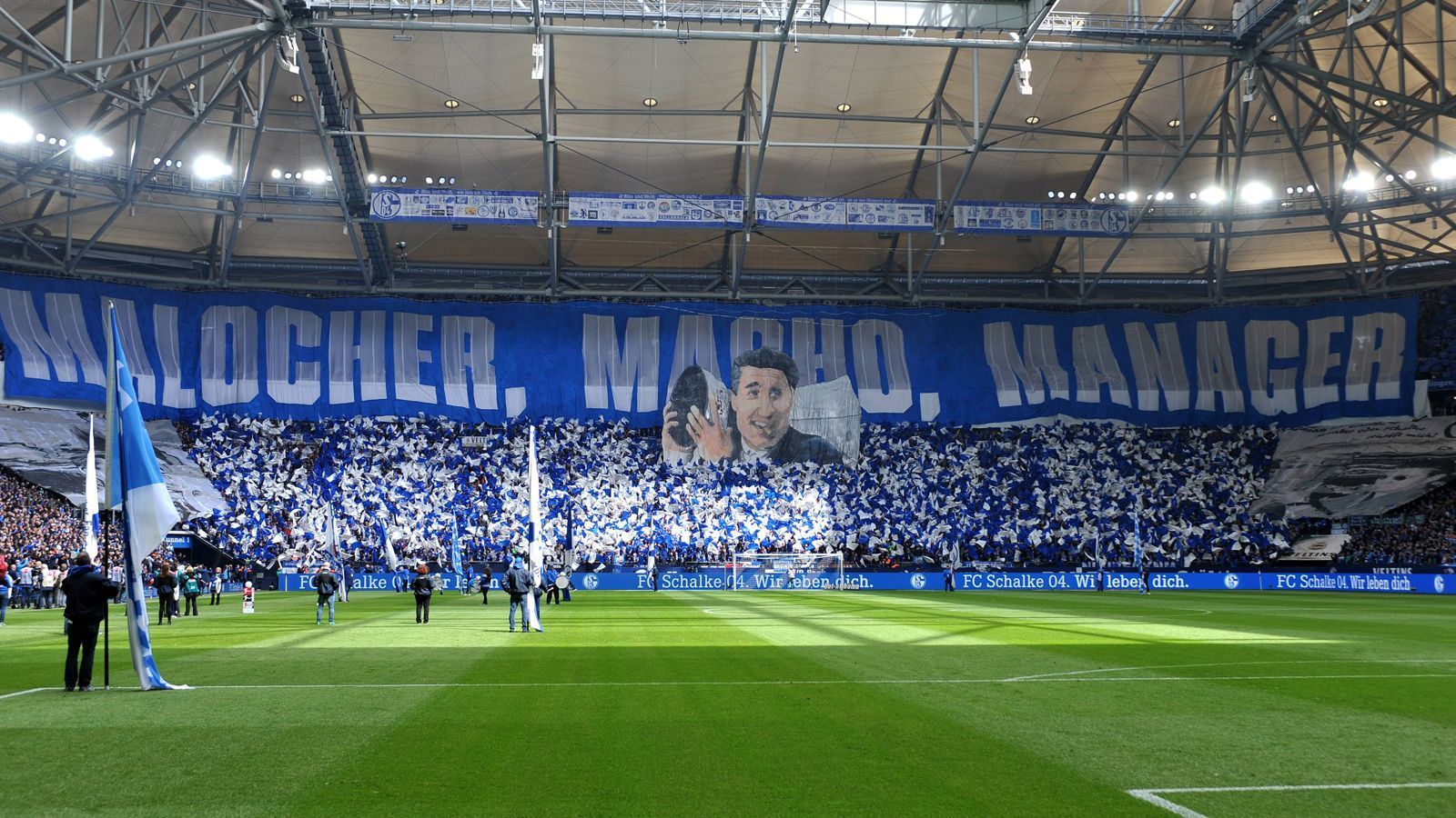 
                <strong>"Malocher, Macho, Manager" - Schalke-Fans feiern Ex-Manager Rudi Assauer</strong><br>
                Vor dem Heimspiel des FC Schalke 04 gegen den FC Augsburg am 32. Spieltag der Bundesliga-Saison 2018/19 gedachte der Anhang der Gastgeber dem Ex-Manager Rudi Assauer. Die Kurve enthüllte dafür ein Spruchband mit der Aufschrift "Malocher, Macho, Manager", um den im Februar 2019 verstorbenen Assauer zu ehren. Am 30. April 2019 wäre Assauer 75 Jahre alt geworden. Unter seiner Führung gewannen die Gelsenkirchener unter anderem 1997 den UEFA-Cup und er war maßgeblich mitverantwortlich für den Bau der Veltins-Arena.
              