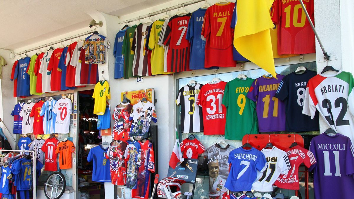 Fußballtrikots aller möglicher Superstars hängen im Außenbereich eines Fanshops. o0 Fanshop Shop Kommerz Merchandising Totale
