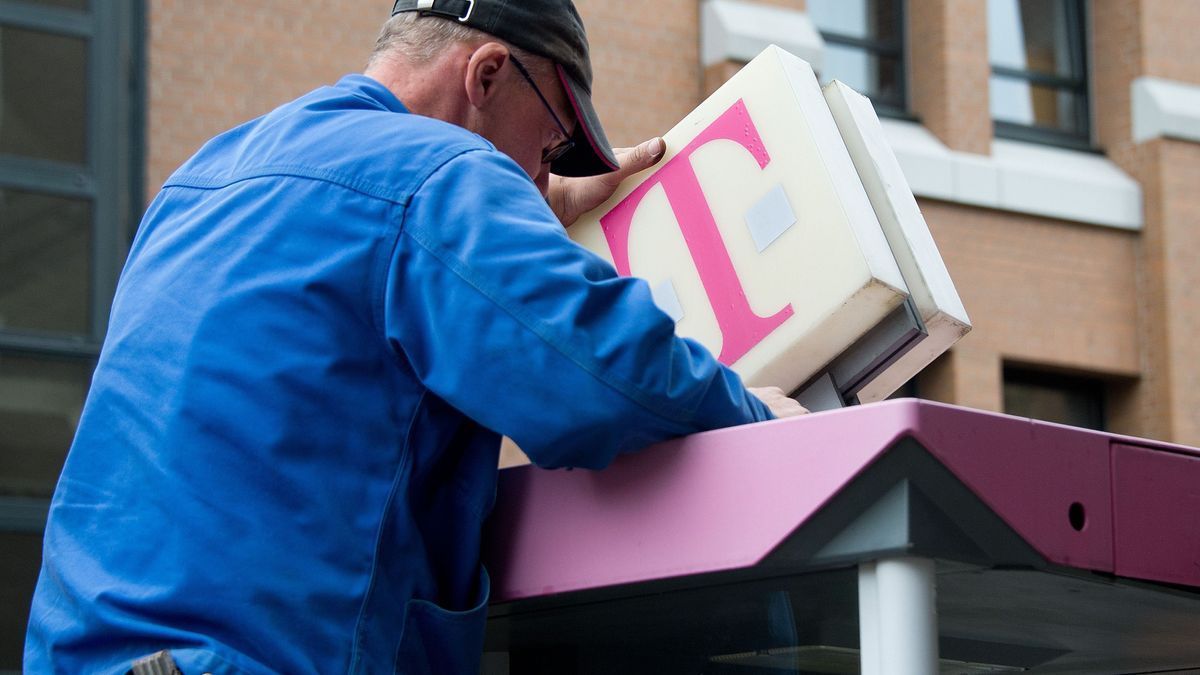 Ein Arbeiter baut eine Telefonzelle der Deutschen Telekom ab.