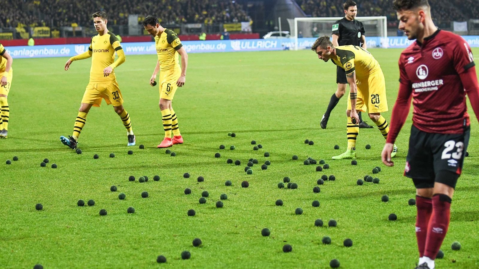 
                <strong>Nürnberger Fans protestieren gegen DFB</strong><br>
                Auch wurden gleich dreimal im ersten Durchgang zahlreiche schwarzgefärbte Tennisbälle auf den Platz geworden, wodurch die Partie immer wieder unterbrochen werden musste. Auch wurde ein Plakat gezeigt mit der Aufschrift: "2 Mal montags, 2 Mal in Nürnberg? DFL, DFB und Co.: Wir rauchen euch in der Pfeife".
              