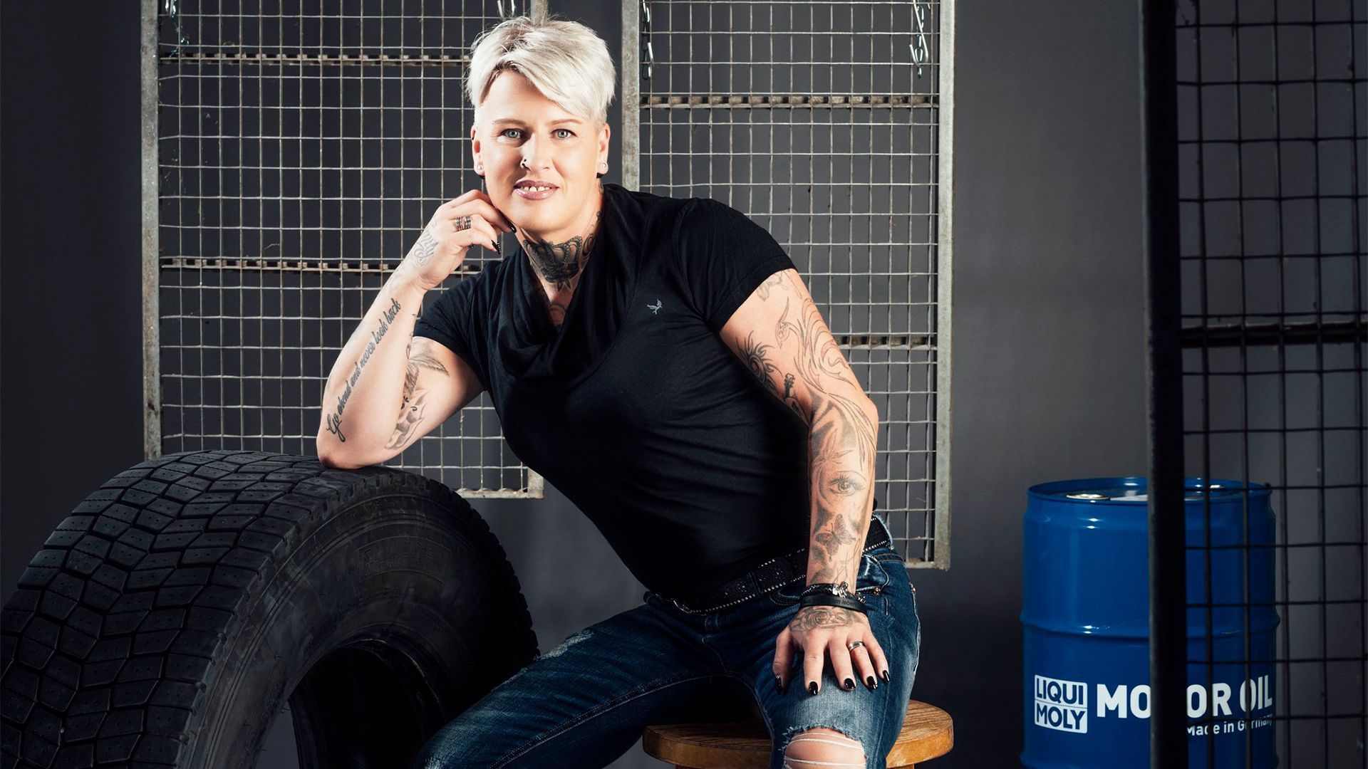 Bei einem Fotoshooting posiert "Trucker Babe" Jana vor einer dunklen Wand und lächelt in die Kamera. 
