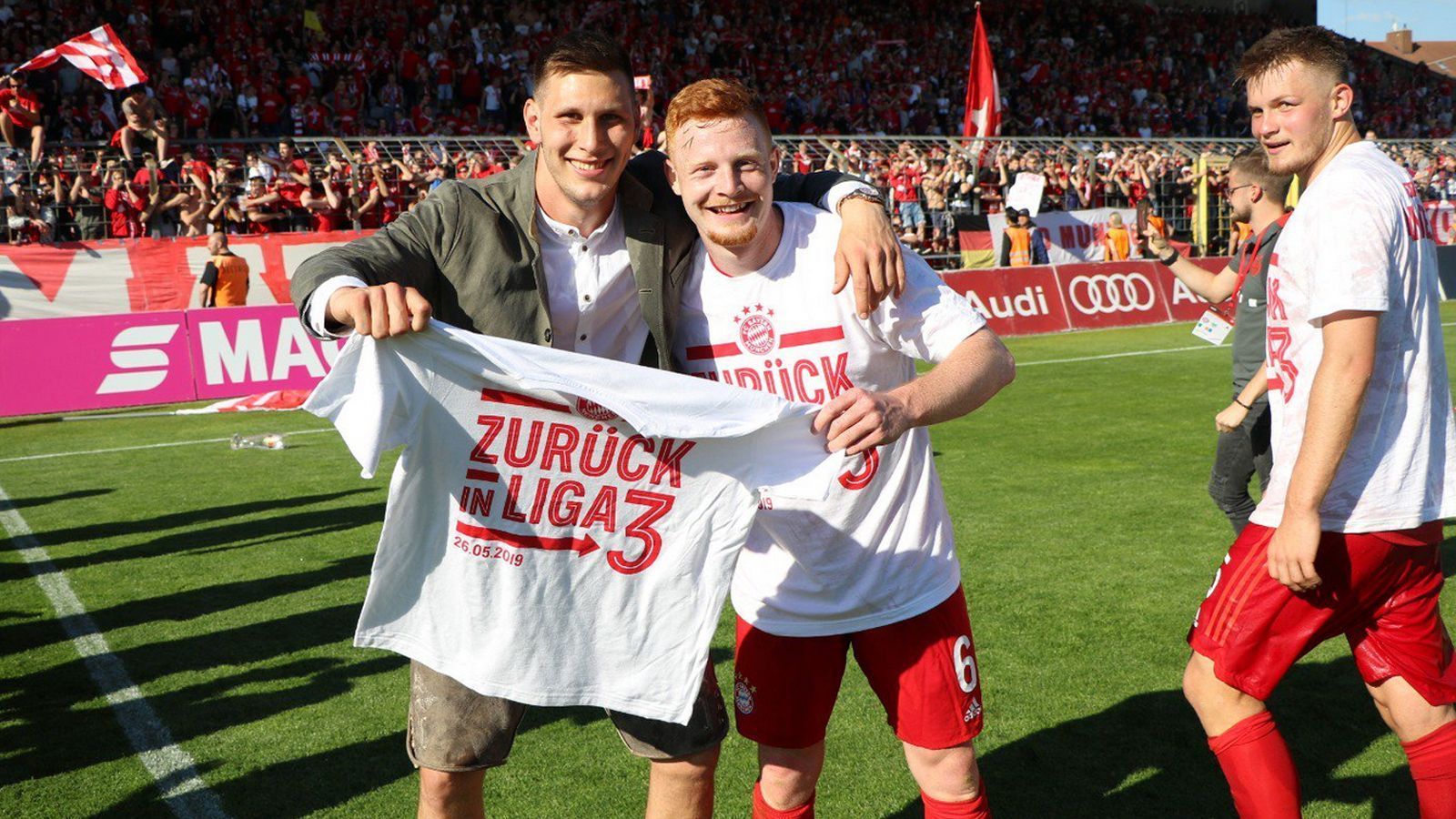 
                <strong>Double und Aufstieg der Amateure: Die Bayern feiern</strong><br>
                Niklas Süle (hier neben Paul Will) war nach dem Abpfiff einer der ersten auf dem Platz - und sicherte sich gleich eins der begehrten Aufstiegs-T-Shirts.
              