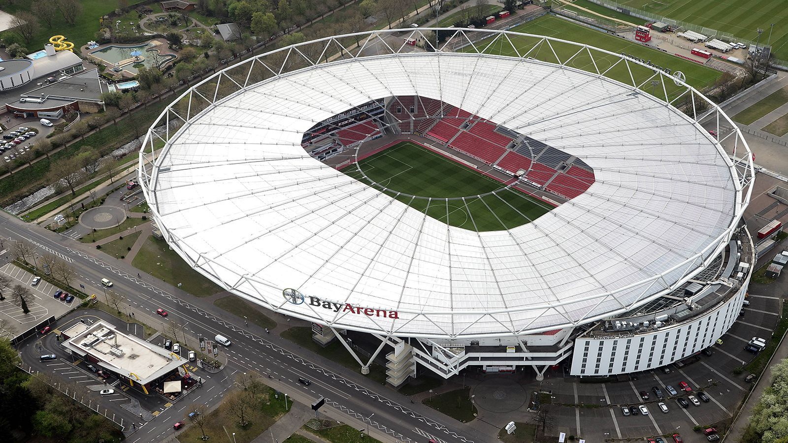 
                <strong>Bayer Leverkusen: Hotel im Stadion und Soccercourt</strong><br>
                Obwohl die Werkself regelmäßig um die europäischen Plätze kämpft, ist die BayArena das sechstkleinste Stadion der Liga. Dennoch kann die Arena durch ihre Bauweise punkten. Das Stadiondach ist - nicht wie gewohnt - auf den Tribünen angebracht, sondern trägt sich selbst. Das ins Stadion integrierte Hotel mit Blick auf das Spielfeld ist ein absolutes Highlight. Außerdem befindet sich zwischen beiden Kabinen ein Soccercourt.   
              