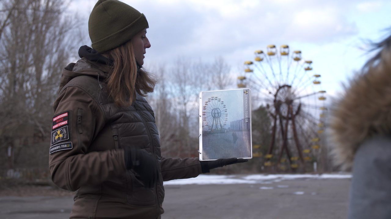 Eine Führerin zeigt den Toouristen, wie ein Riesenrad in der Stadt Pripjat früher aussah - und heute.