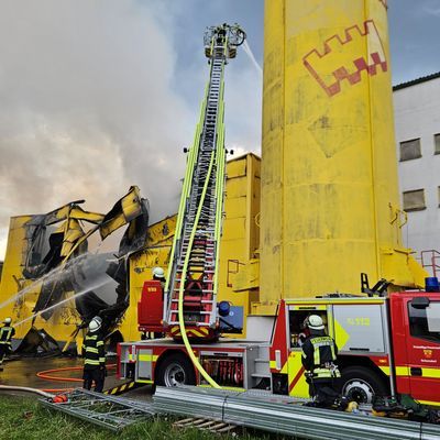 Einsätzkräfter der Feuerwehr löschen eine in Brand geratene Lagerhalle von einem Spielehersteller.