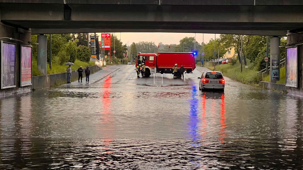 Ein Einsatzfahrzeug der Feuerwehr sichert eine mit Regenwasser vollgelaufene Unterführung ab.