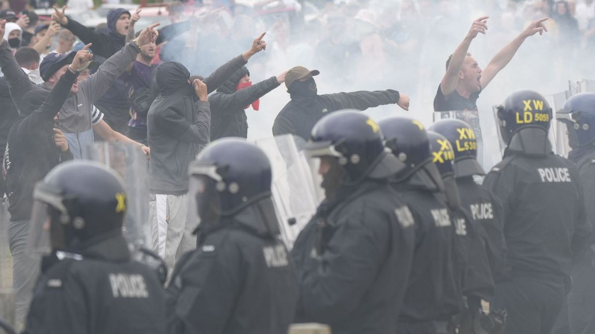 4. August 2024, Großbritannien, Rotherham: Polizisten stehen vor Randalierern bei gewalttätigen Auseinandersetzungen an einem Hotel, in dem Asylbewerber:innen untergebracht sind. 