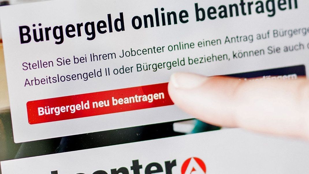 Eine Frau tippt auf einem Tablet auf einen Link zum Beantragen des Bürgergeldes im Kundenbereich im Jobcenter Berlin-Mitte.  