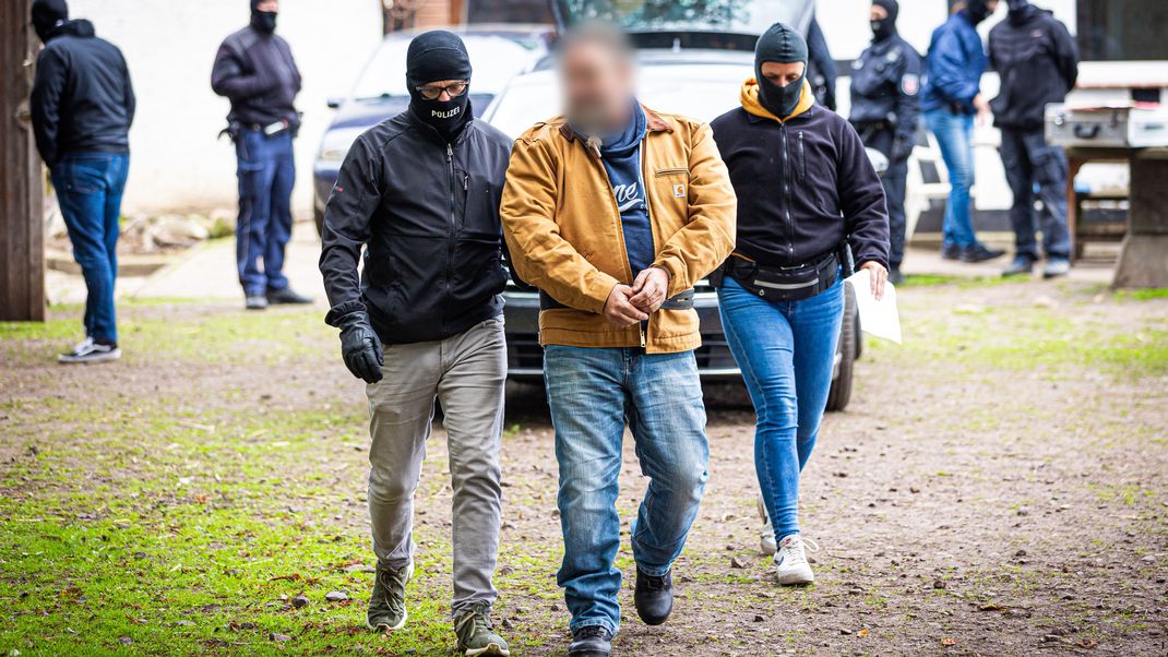 Nordrhein-Westfalen, Espelkamp: Einsatzkräfte der Polizei führen während einer Razzia einen Mann ab. 