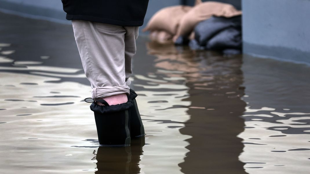 Ein Anwohner steht mit Gummistiefeln im Hochwasser der Mindel im bayerischen Burgau. 