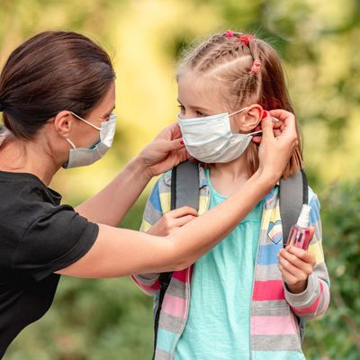 Mother putting mask on daughter before school