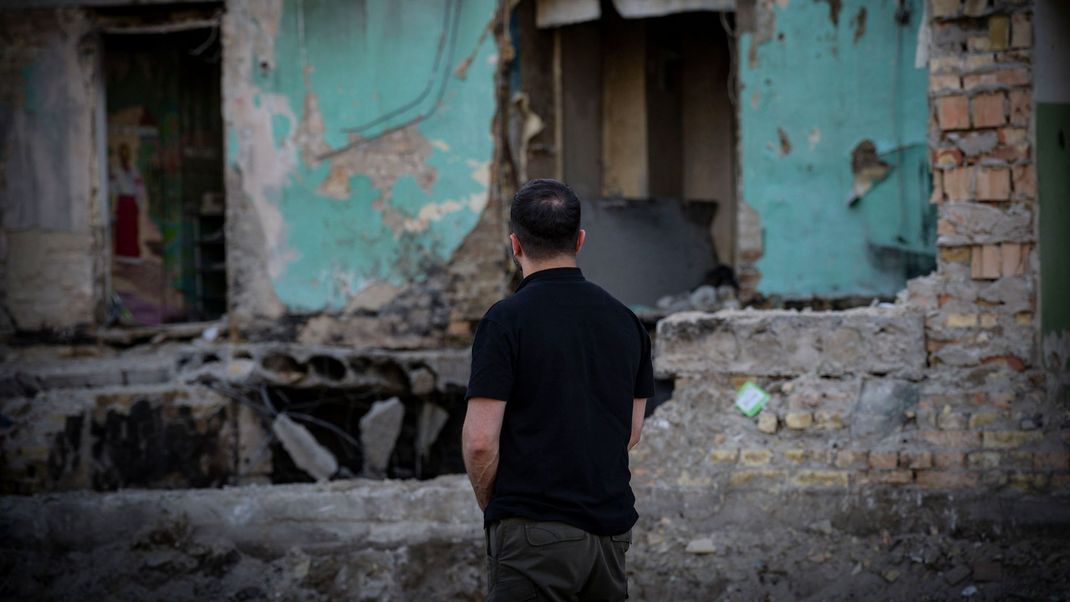 Präsident Selenskyj vor einem zerbombten Wohnhaus in der Ukraine – das Land steht weiter unter russischem Dauerbeschuss.