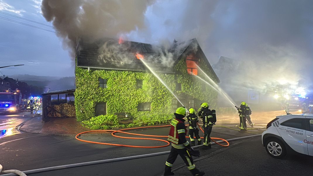 Einsatzkräfte löschen ein bewachsenes Haus. Bei dem Brand in einem Mehrparteienhaus im Sauerland sind mehrere Menschen verletzt worden. 