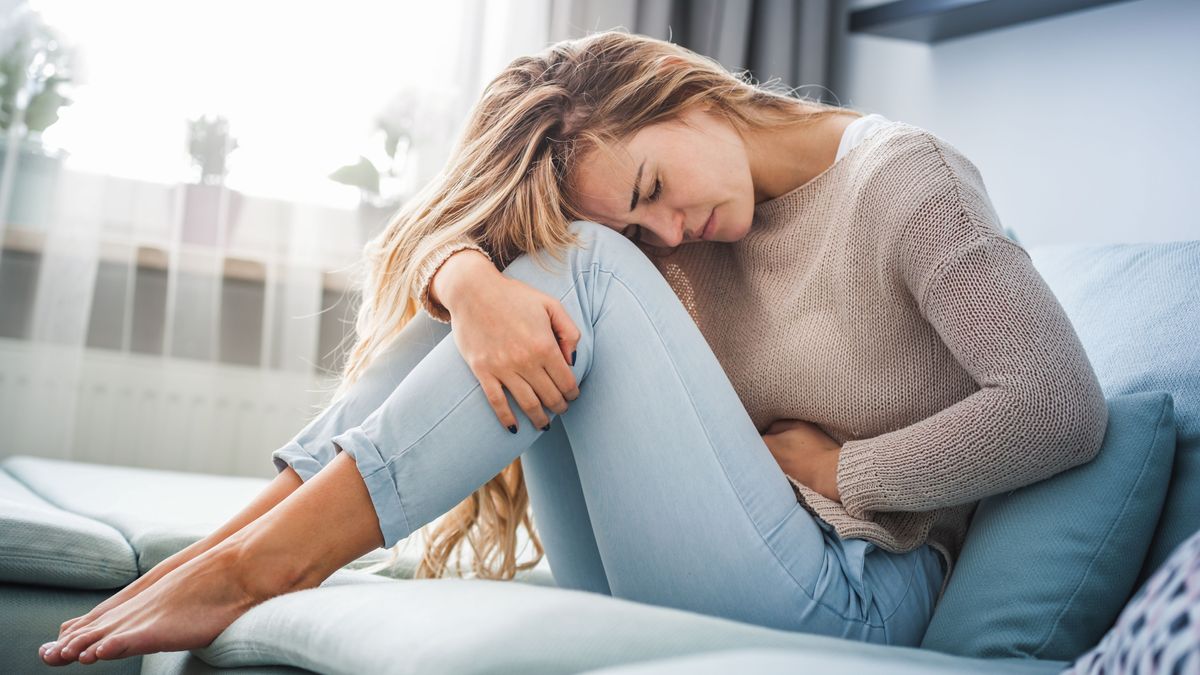 Eine Frau sitzt gekrümmt auf einem Sofa