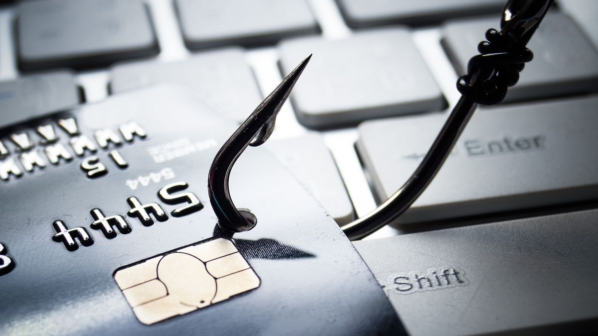 credit card phishing - piles of credit cards with a fish hook on computer keyboard