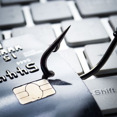 credit card phishing - piles of credit cards with a fish hook on computer keyboard