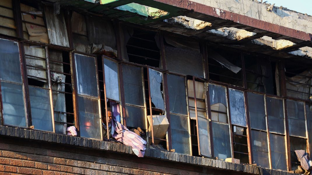 Ein Bewohner schaut aus dem Fenster, in der Nähe des Gebäudes, das in Johannesburg am Donnerstag abgebrannt ist.