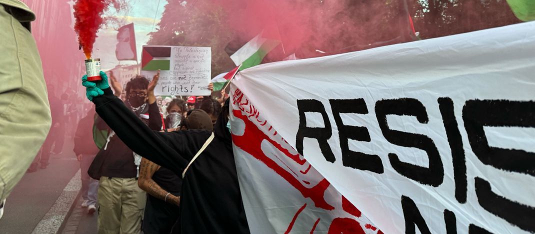 Basel: Menschen halten bei einer Pro-Palästina-Demonstration Banner und Flaggen und lassen bunten Rauch aufsteigen auf einer Straße in der Stadt am Tag des großen Finales des 69. Eurovision Song Contest (ESC).