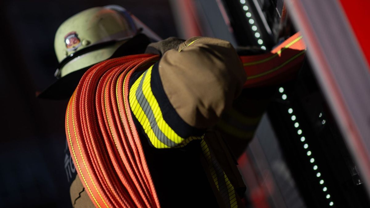 Ein Feuerwehrmann holt einen Schlauch aus einem Einsatzfahrzeug