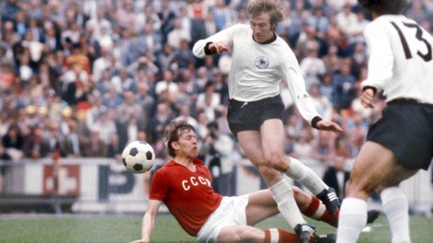 
                <strong>EM 1972 (Günther Netzer)</strong><br>
                EM 1972: Während der Europameisterschaft in Belgien tragen Günther Netzer und die Jungs wieder die klassisch-weißen Trikots mit Rundhalsauschnitt. Und die bringen Glück: Deutschland holt 1972 seinen ersten EM-Titel.
              