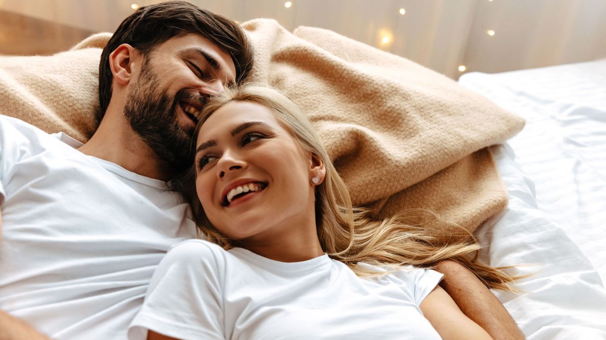 Love. Fun. Emotions. Young couple are laughing while lying together on the bed