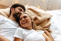 Love. Fun. Emotions. Young couple are laughing while lying together on the bed