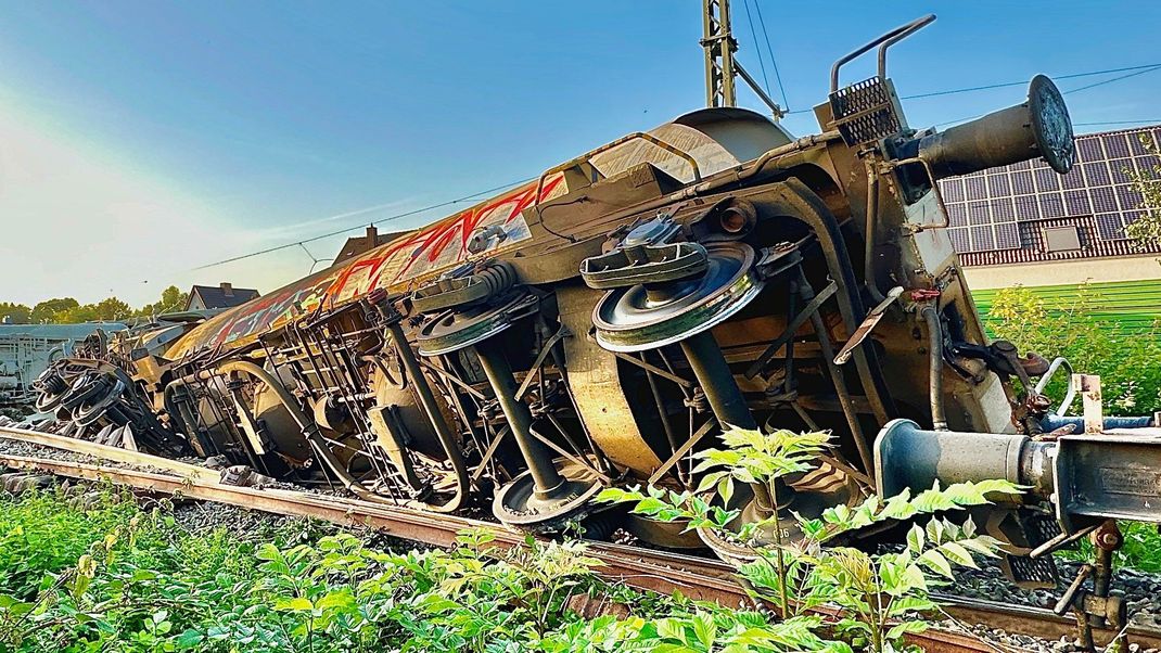 Teile eines entgleisten Güterzuges sind an der Bahnstrecke zu sehen. 