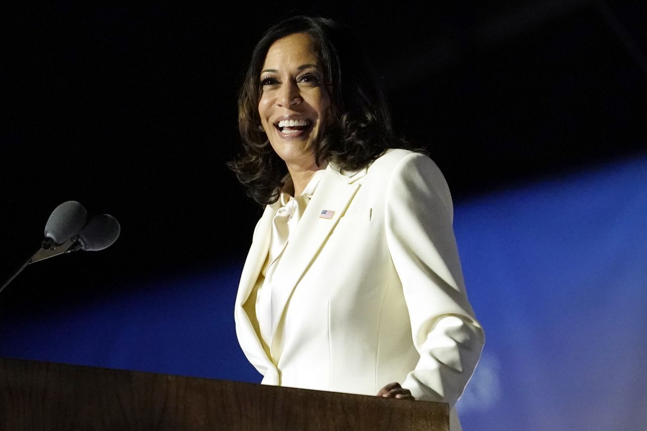 Kamala Harris, "Vicepresident Elect", hält eine Ansprache.  Der weiße Anzug hat Symbolkraft: seit Beginn des 20. Jahrhunderts hatte die Frauenrechts-Bewegung der Suffragetten, die für das Frauenwahlrecht kämpfte, weiß als Farbe reklamiert. 