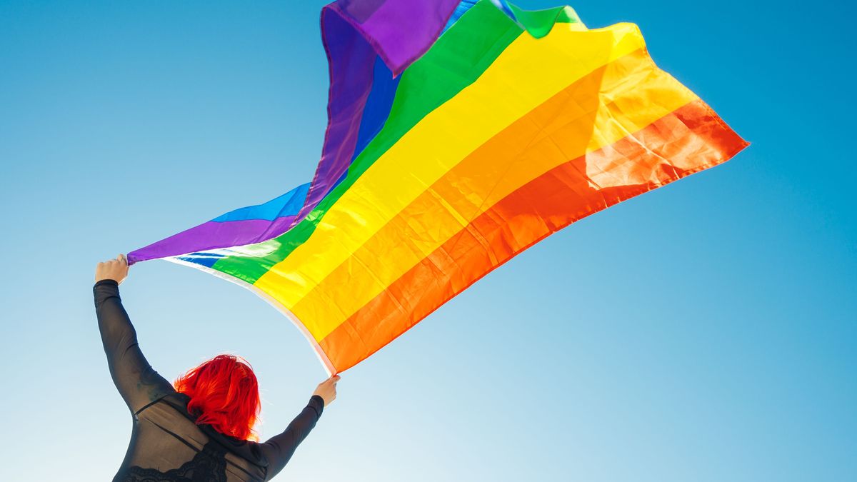 Woman on her back with open arms waving an lgbt flag