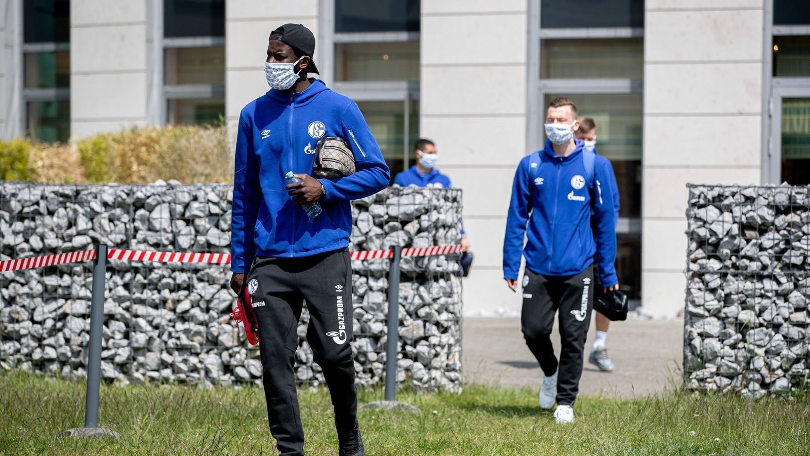 
                <strong>Die kuriosen Bilder des Bundesliga-Restarts</strong><br>
                Bereits bei der Anreise zum Stadion halten die Schalker Abstand auf dem Weg zum Bus. 
              