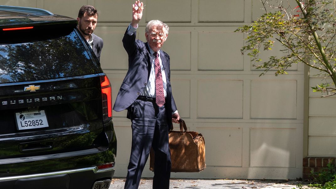 Der ehemalige nationale Sicherheitsberater John Bolton kommt bei seinem Haus in Bethesda an und winkt zu den Medienvertretern. Boltons Haus wurde von FBI-Agenten durchsucht.
