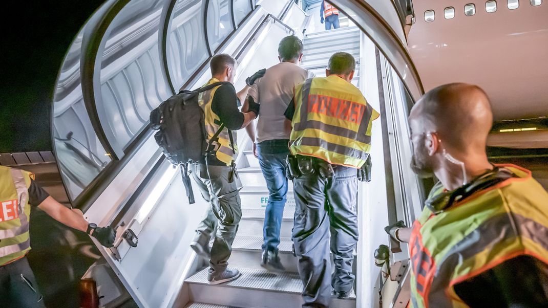Polizeibeamte begleiten einen Afghanen auf dem Flughafen Leipzig-Halle in ein Charterflugzeug. 