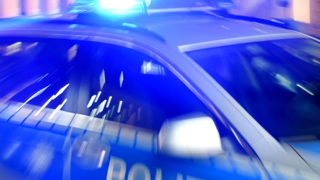 Ein Streifenwagen der Polizei steht mit eingeschaltetem Blaulicht auf der Straße.