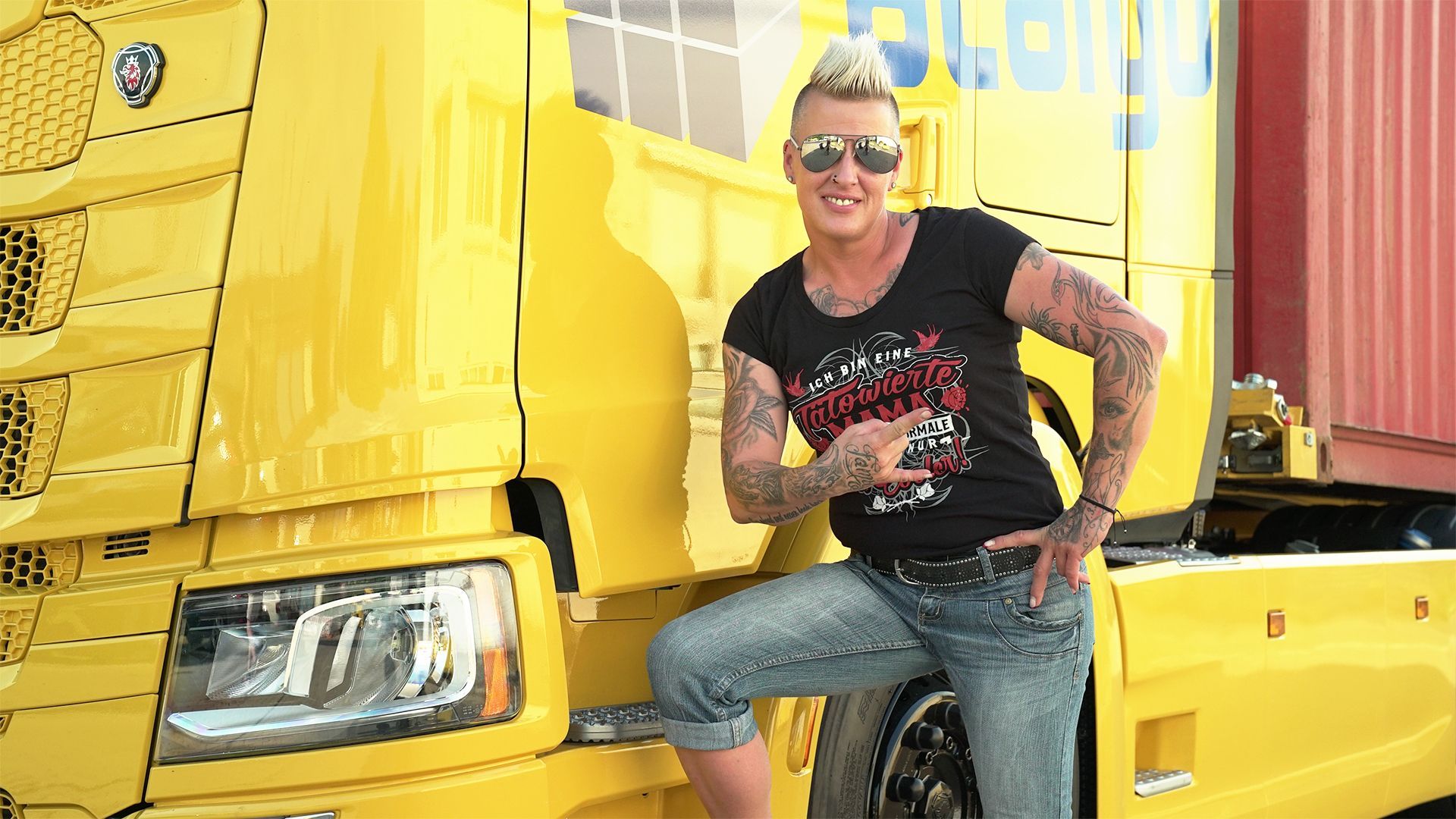 "Trucker Babe" und "Chaos-Queen" Jana lehnt an dem Fahrerhaus ihres gelben Trucks.&nbsp;