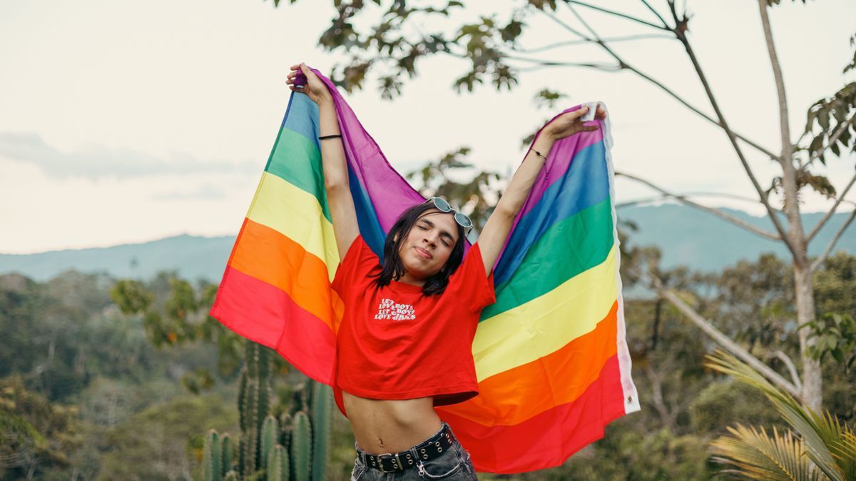 Non-binary activist with a rainbow flag in Peru's jungle