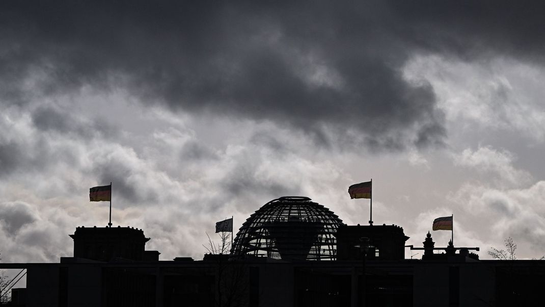 Dunkle Wolken sind über der Kuppel vom Reichstag zu sehen.