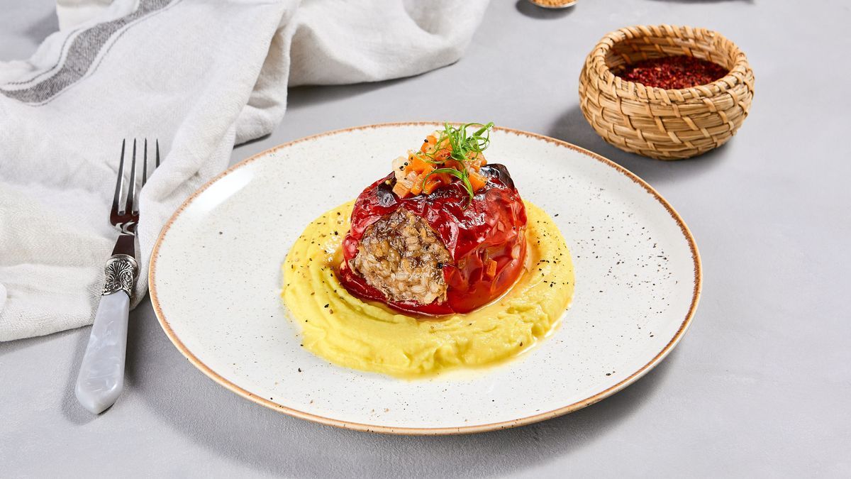 Eastern cuisine - stuffed paprika with mashed potatoes. Stuffed pepper with pure on ceramic plate in contemporary style. Modern concept eastern food menu. Aesthetic composition with main course.