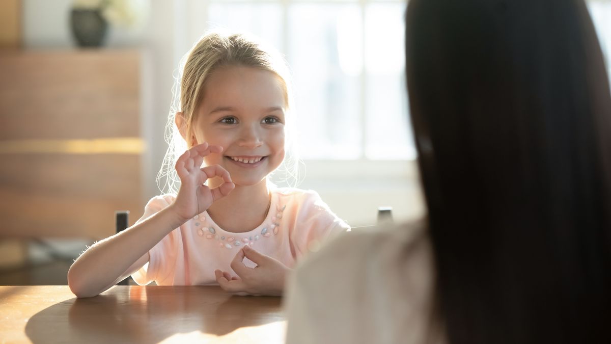 Happy little girl practice sign language with mom