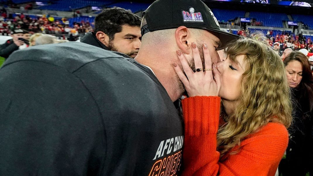 Taylor Swift küsst Travis Kelce, Tight End der Kansas City Chiefs, nach seinem Sieg auf dem Spielfeld.