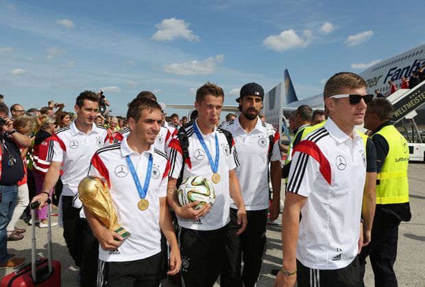 
                <strong>Mit Pokal und Ball</strong><br>
                Mit Pokal und Ball machen sich Toni Kroos, Sami Khedira, Erik Durm, Philipp Lahm und Miroslav Klose auf den Weg in den Bus.
              